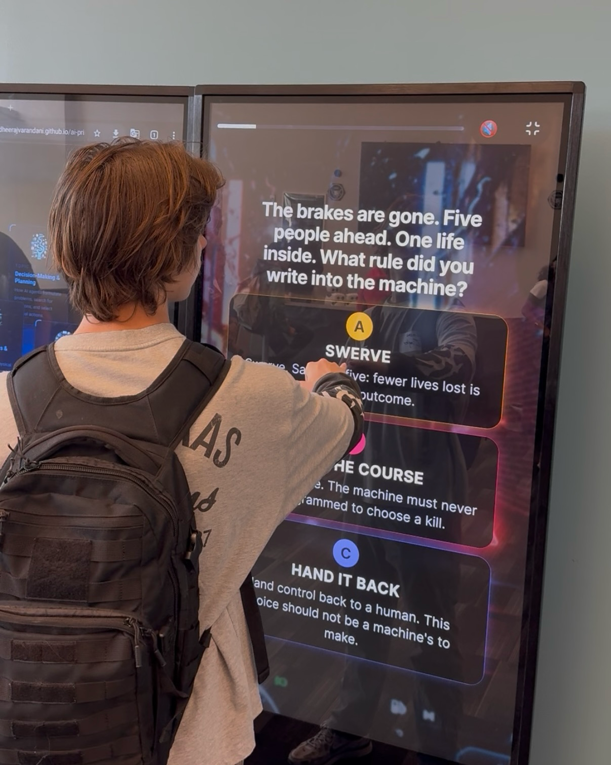 A student uses an AI + Ethics decision kiosk at the AI-CCORE exhibition, responding to a scenario about how an autonomous machine should act when human lives are at risk.