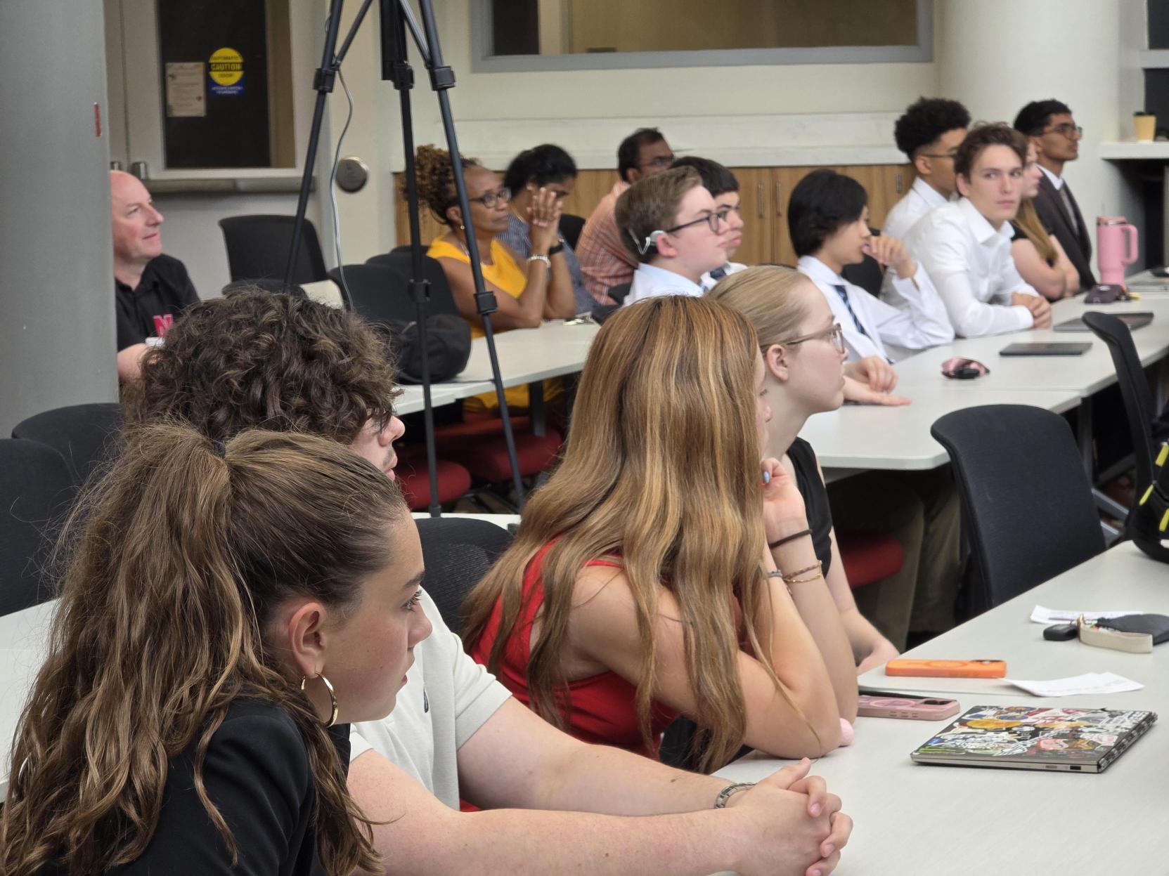 High schoolers take in a fellow team's presentation during demo day.